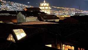 Vista nocturna de un pueblo con tejados iluminados y un edificio destacado con una cruz en la parte superior.