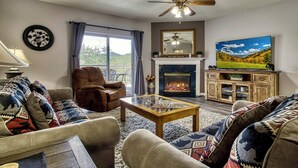 A living room with a fireplace, a television, and a ceiling fan.