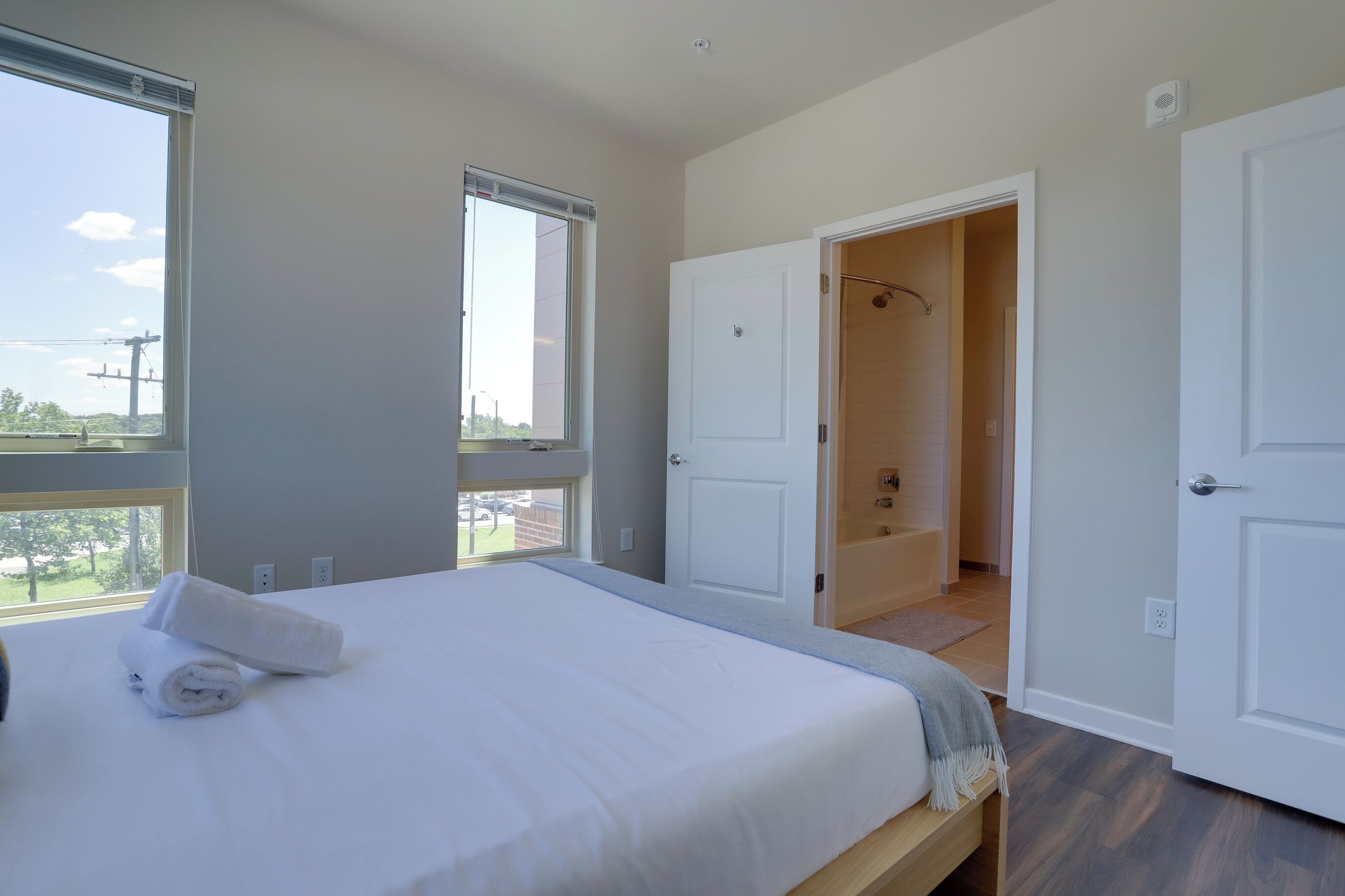 Ein Schlafzimmer mit einem Bett, einem Fenster und einer offenen Tür zu einem Badezimmer.