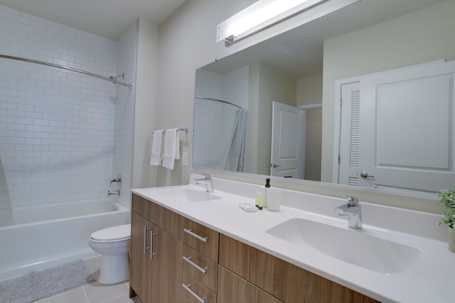 A modern bathroom with a white bathtub, a separate shower area, and a vanity with a large mirror.