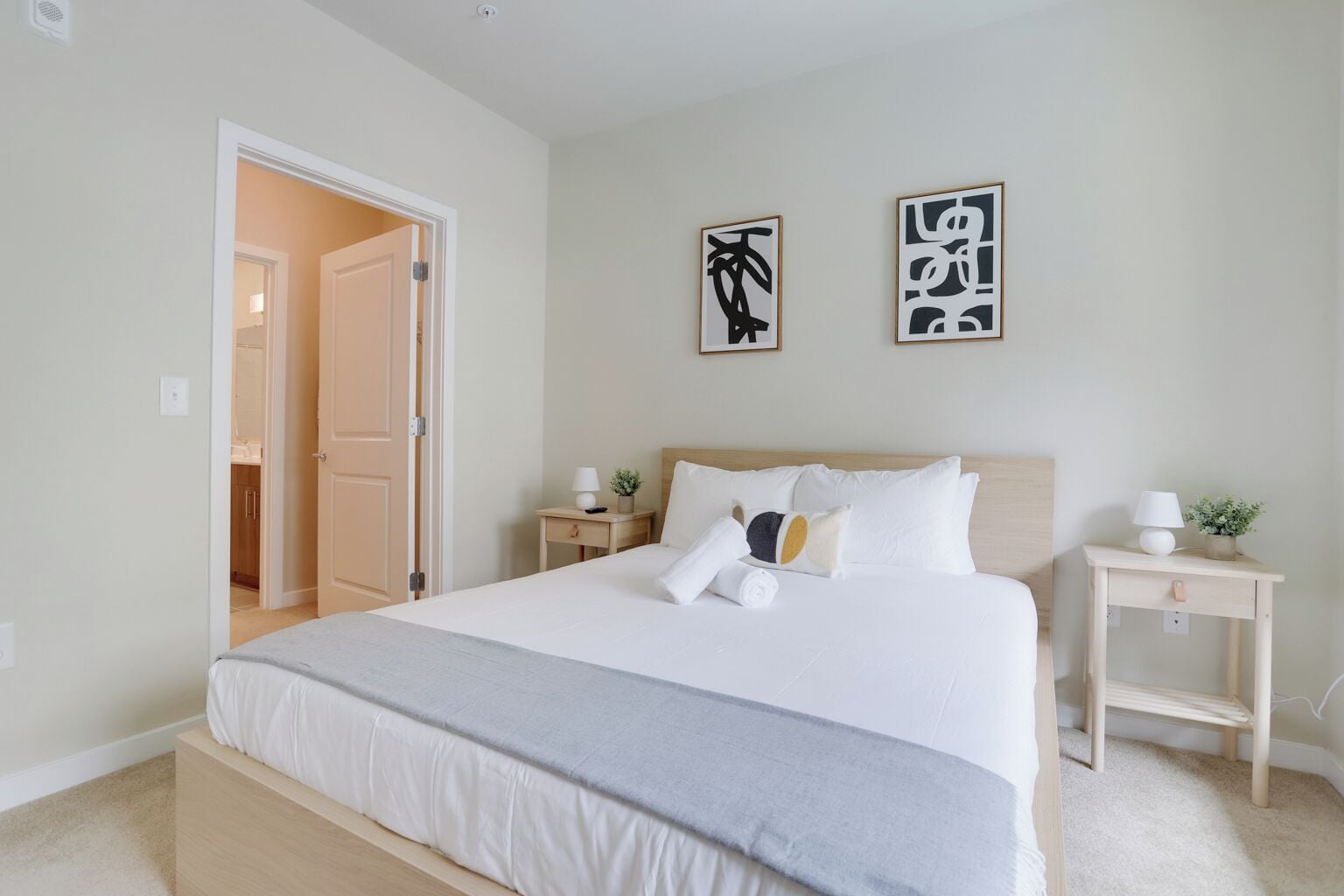 A bedroom with a large bed, bedside tables, and a door leading to another room.