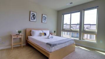 A bedroom with a large bed, two bedside tables, a small plant, and two framed pictures on the wall.