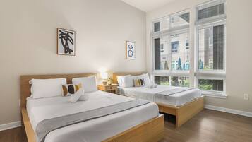 Une chambre d’hôtel avec deux lits, une grande fenêtre avec des stores et des œuvres d’art accrochées au mur.