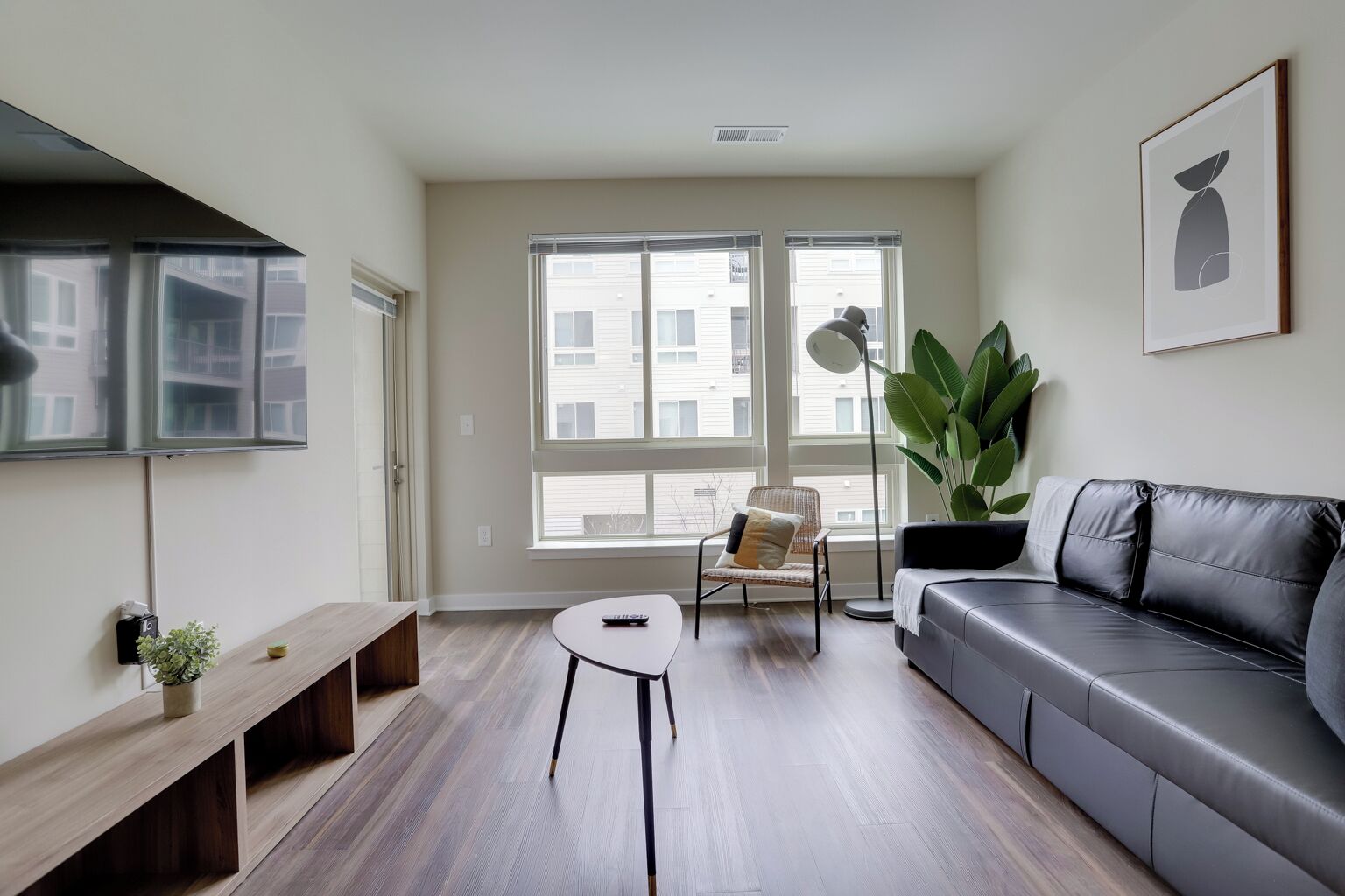 Een moderne woonkamer met een bank, een fauteuil, een bijzettafeltje en een groot raam.