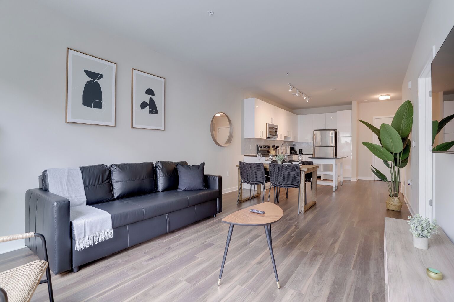 A modern living room with a grey sofa, a coffee table, and a dining area with chairs.