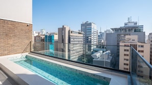Une piscine sur le toit offrant une vue sur la ville, entourée d’immeubles modernes.