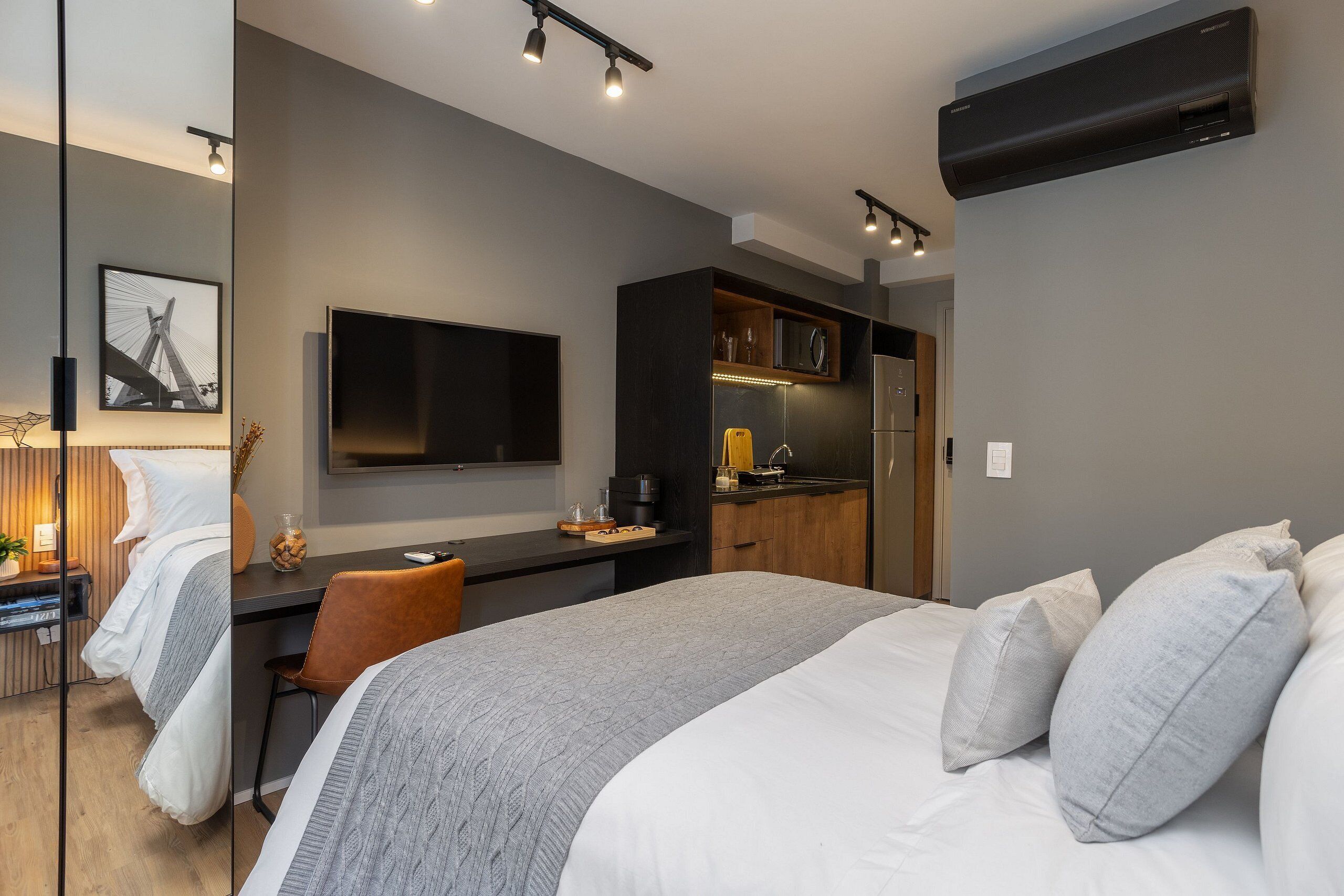 Una habitación de hotel moderna con cama, escritorio y kitchenette.