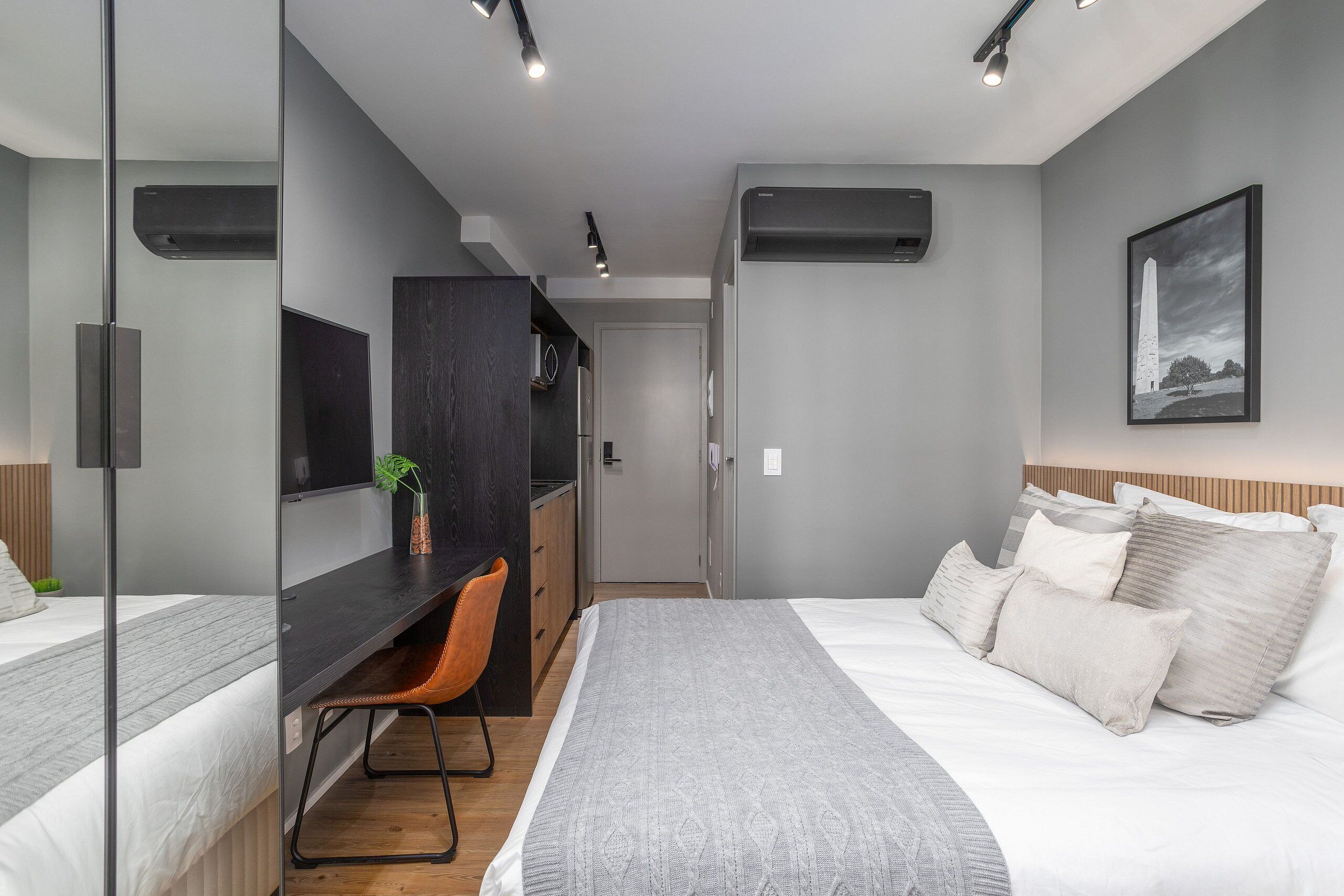 A modern bedroom with a bed, a desk, and a chair.