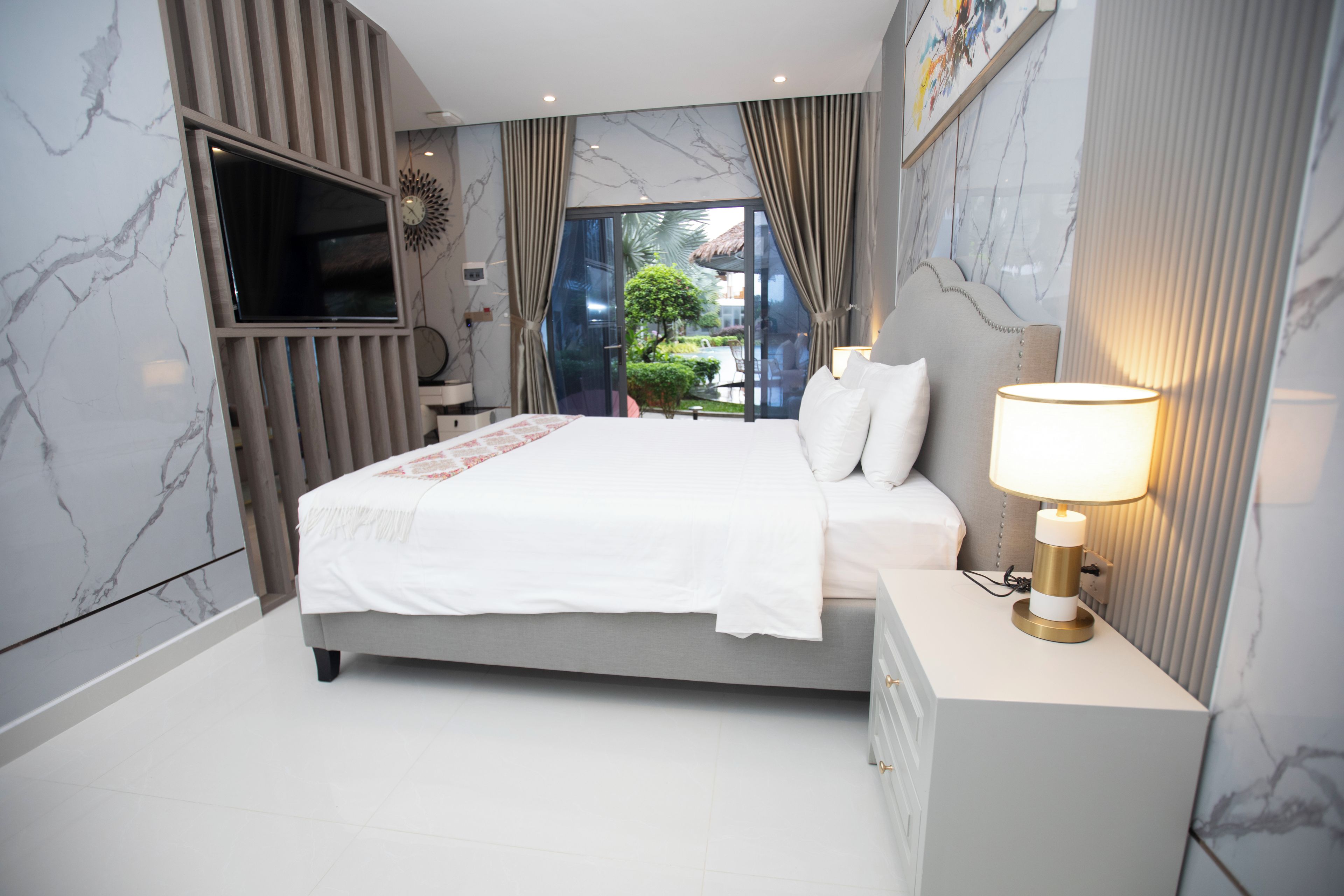 Ein modernes Schlafzimmer mit Bett, Nachttisch und einem an der Wand befestigten Fernseher.