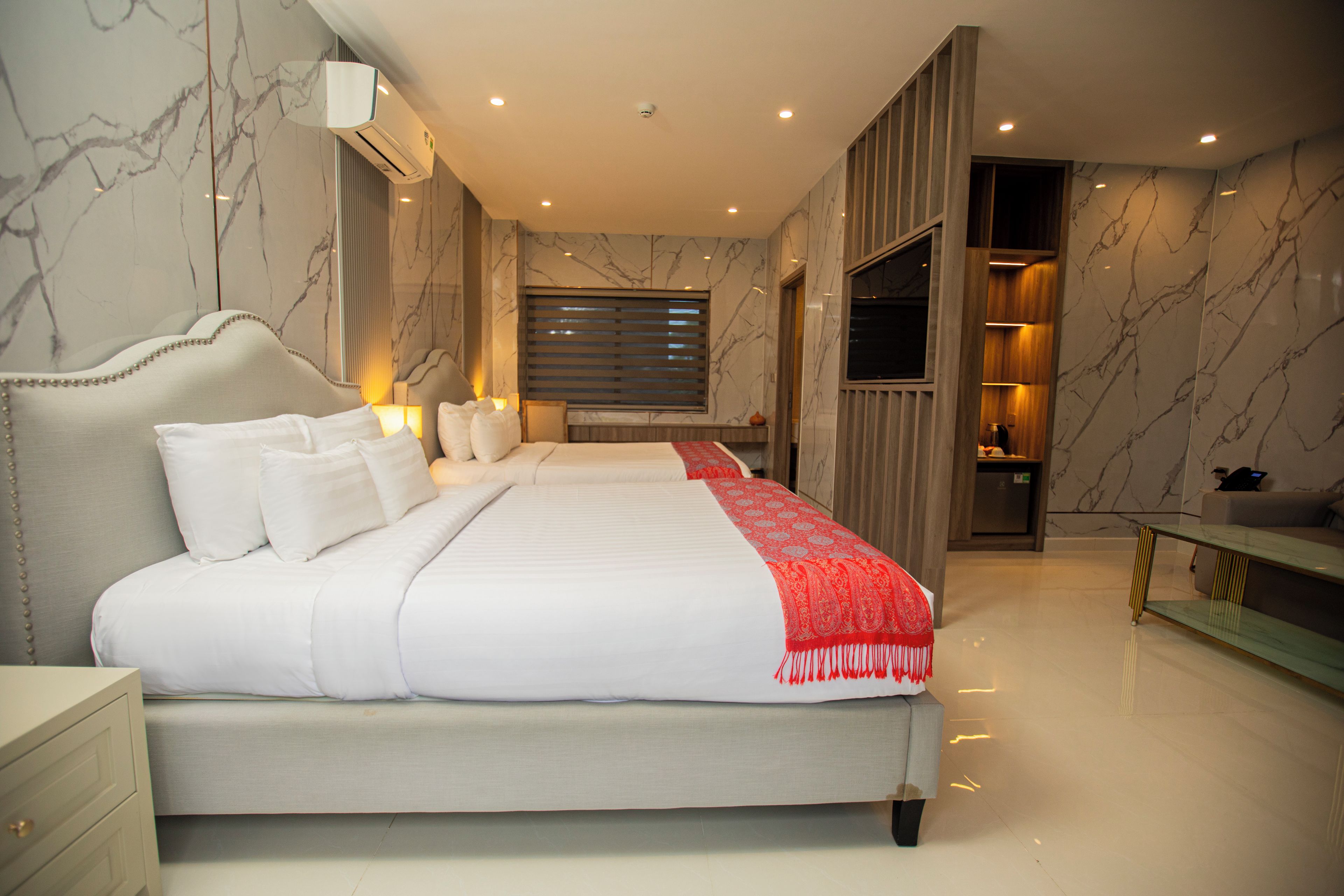 Un dormitorio moderno con una cama grande, mesitas de noche, tocador y vestidor.