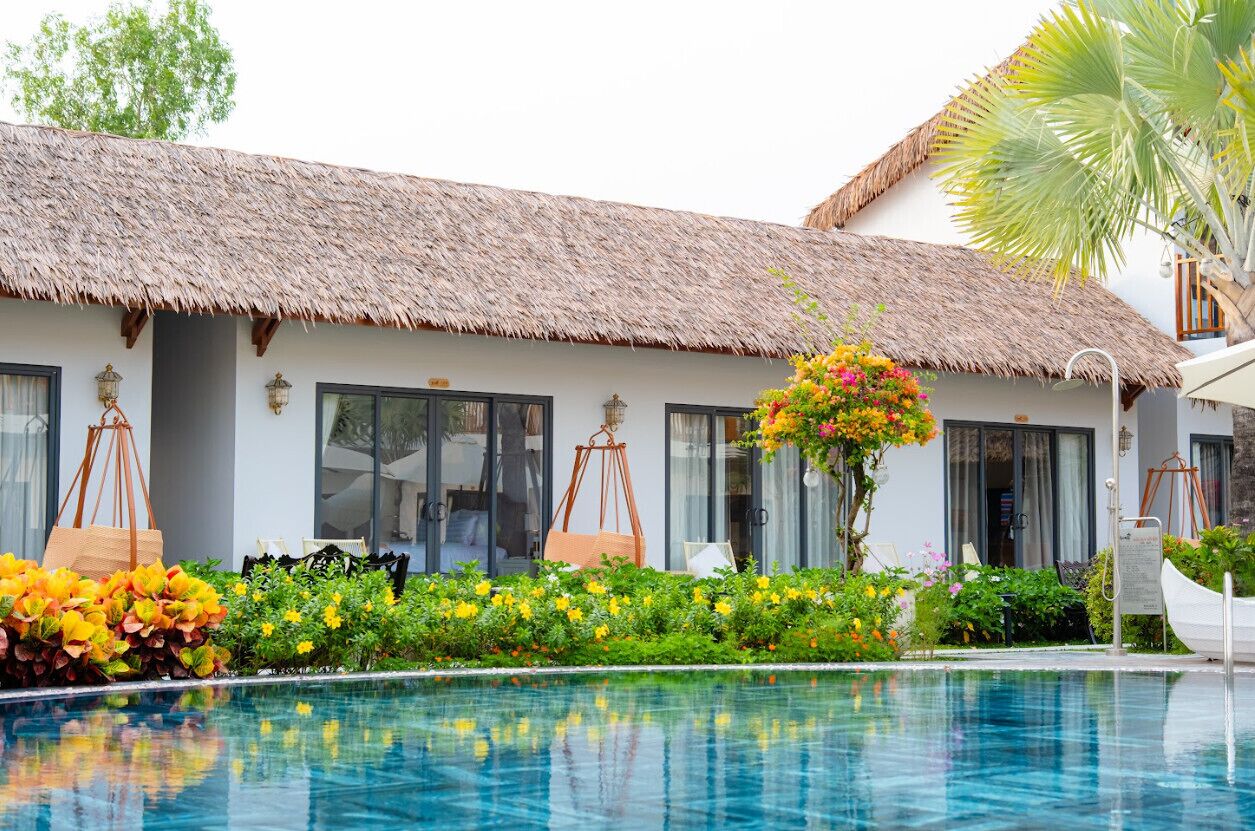 Un resort con piscina, edificación de techo de paja y exuberante jardín.