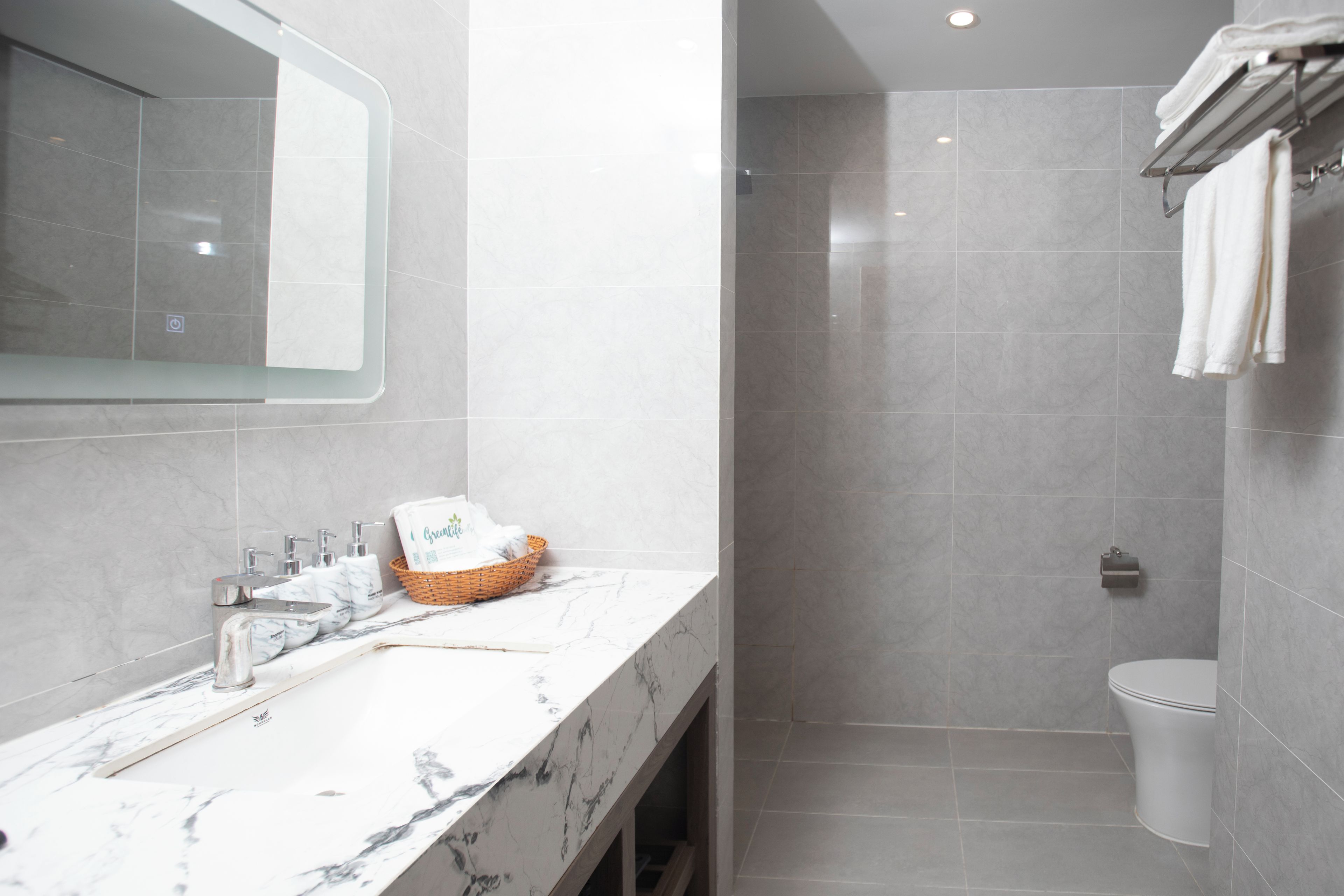 A modern bathroom with a marble countertop, a shower area, and a toilet.