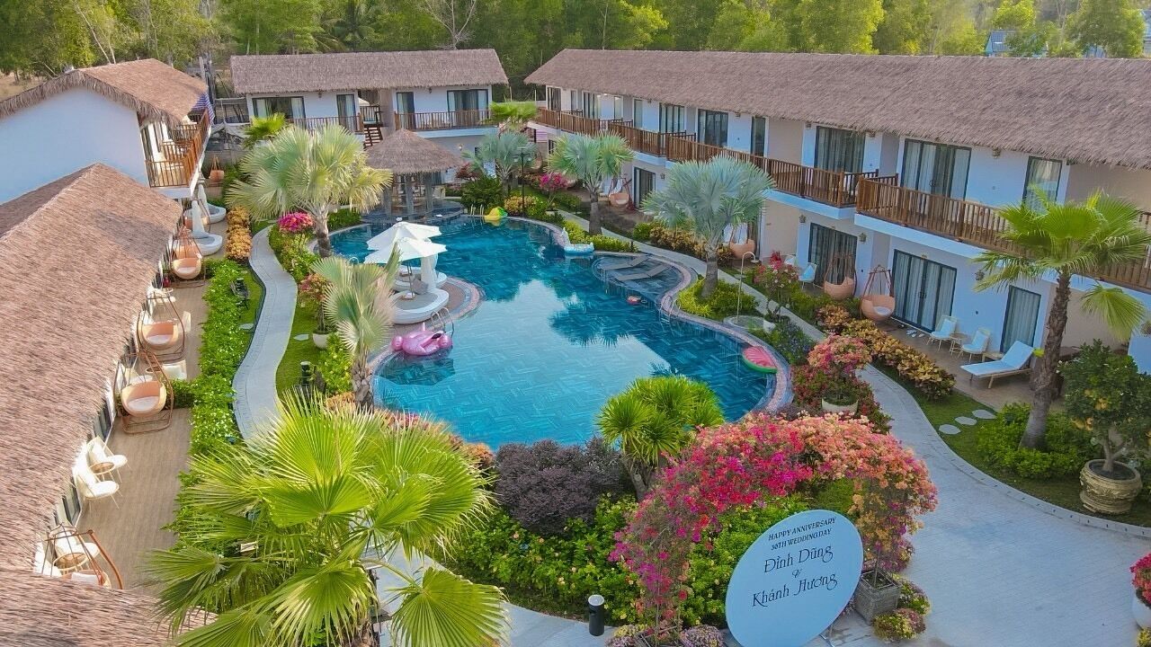 A resort with a central swimming pool, multiple bungalow-style accommodations, and lush landscaping.