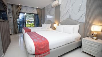 Habitación de hotel con una cama grande, mesitas de noche, equipo de aire acondicionado y vistas a través de un ventanal.