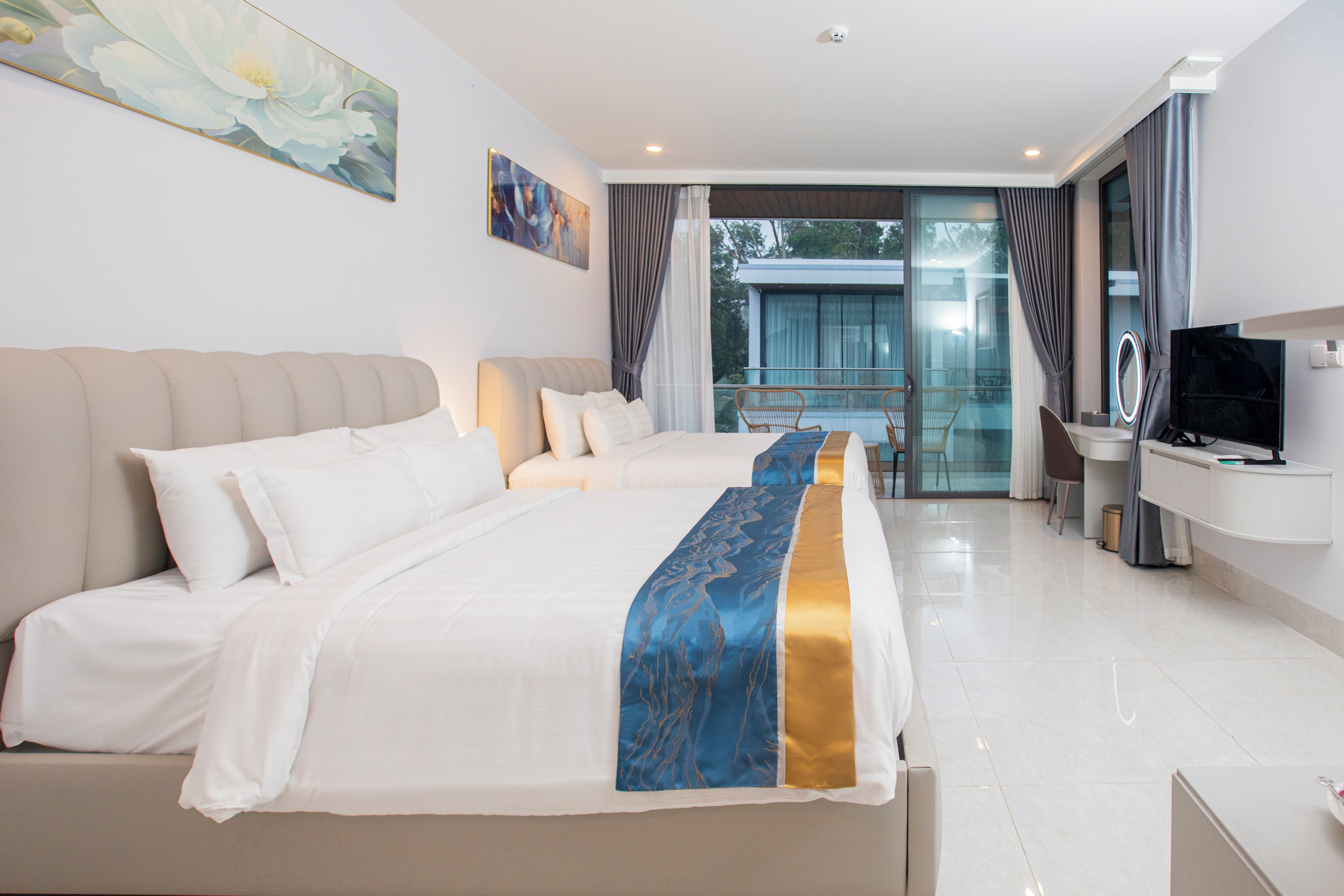 A hotel room with a large bed, a desk with a TV, and a balcony with a view.