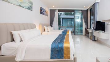 A hotel room with a large bed, a desk with a TV, and a balcony with a view.