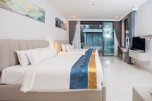 Habitación de hotel con una cama grande, un escritorio con televisor y un balcón con vistas.