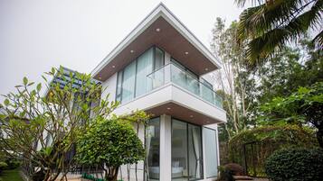 Une maison moderne à deux étages, dotée de grandes fenêtres et d’un jardin bien entretenu.