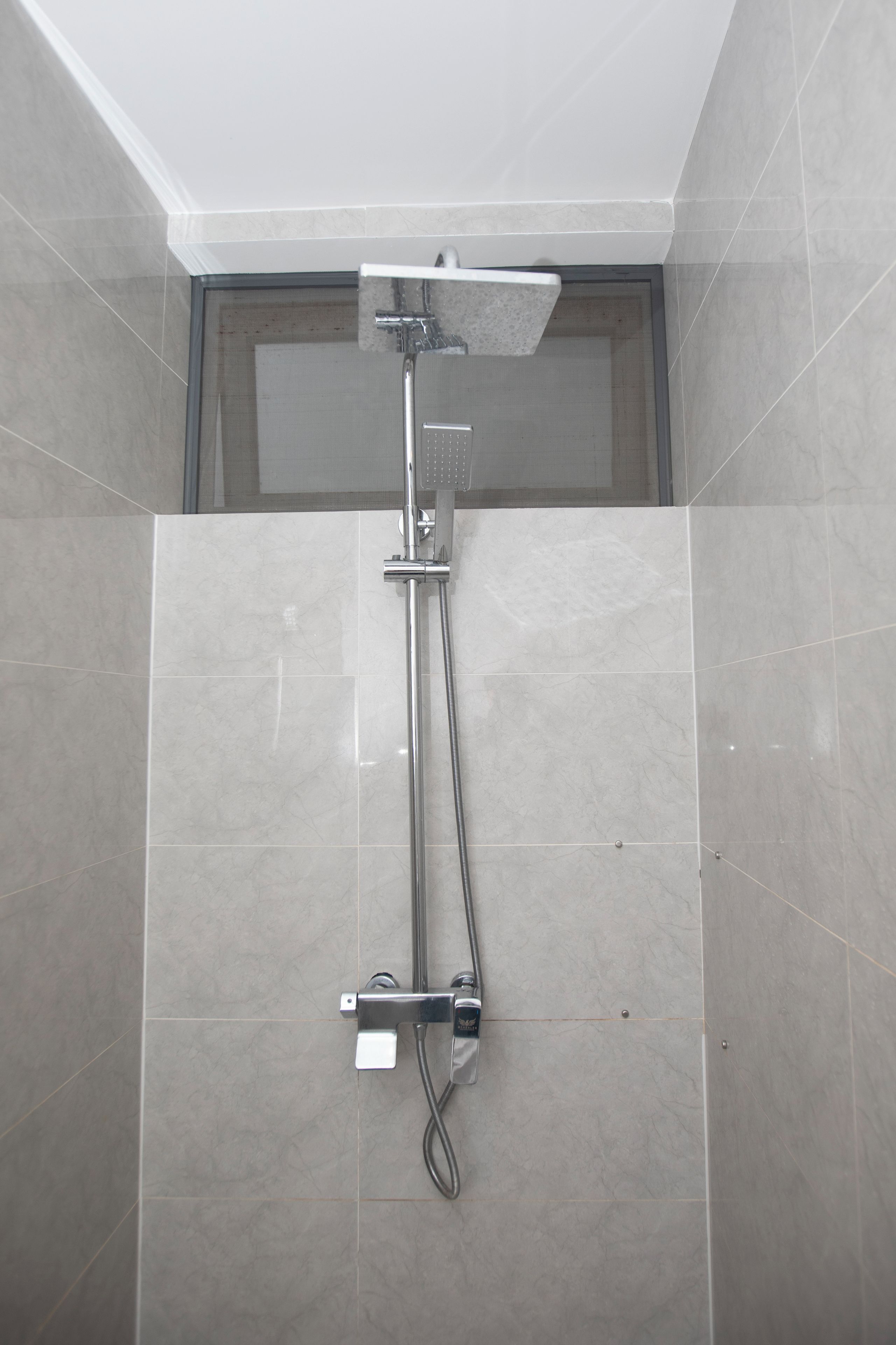 A shower with a handheld showerhead and a fixed overhead showerhead, both mounted on a wall with a tiled floor.