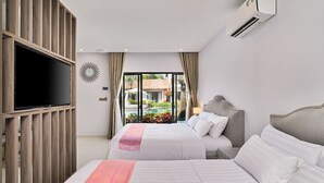 A hotel room with two beds, a TV, and a large window with a view of a garden and a building. - Greenlife Village Phu Quoc (Phu Quoc)