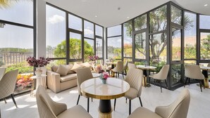 A spacious indoor area with large windows, a round table, and comfortable seating. - Greenlife Village Phu Quoc (Phu Quoc)