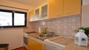 A compact kitchen with a window, a sink, a stove, and a refrigerator. - Greta studio 1 with terrace (Rovinj)