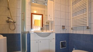 A bathroom with a bathtub, a toilet, and a sink with a mirror above it. - Greta studio 1 with terrace (Rovinj)