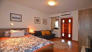 Ein Schlafzimmer mit Bett, Sofa, einem kleinen Tisch und einem Fenster mit Vorhängen.