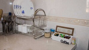 Una cocina con un escurreplatos, utensilios, una cafetera y una caja para café.