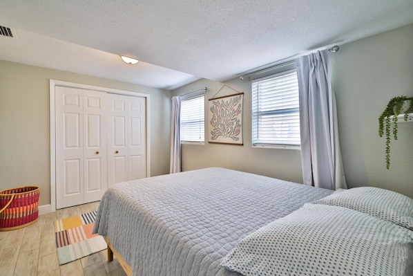 A bedroom with a bed, a wardrobe, a window with curtains, and a wall-mounted plant.
