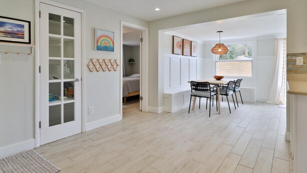 A spacious room with a dining area, a door leading to a bedroom, and a window with a view.