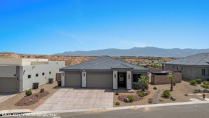 A modern residential building with a garage, surrounded by landscaped gardens and a mountainous backdrop. - Mountains and Saltwater Pool (Mesquite)