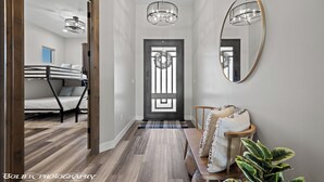 A hallway with a bunk bed, a wooden bench, a mirror, and a door with a wreath. - Mountains and Saltwater Pool (Mesquite)