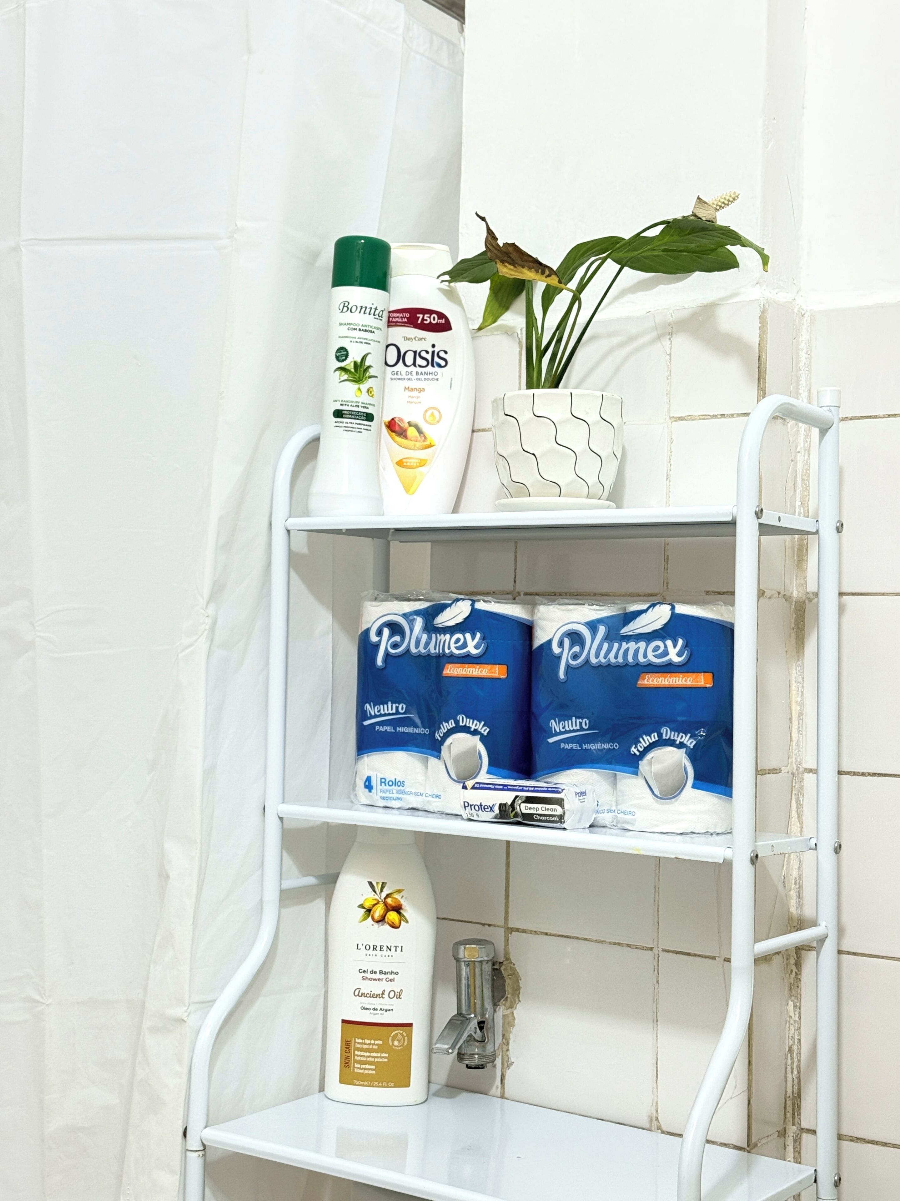 Ein Badezimmerschrank mit verschiedenen Pflegeprodukten, darunter eine Shampooflasche, eine Duschgel-Flasche und Toilettenpapier.