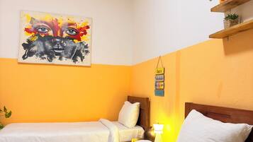 Una habitación de hotel con dos camas, un cuadro en la pared y un estante con objetos decorativos.