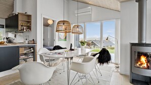 Een moderne keuken met een ingebouwde kookplaat, witte kasten en een eethoek met een ronde tafel en witte stoelen.