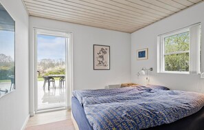 A bedroom with a large bed, a desk, and a chair. There is a window with a view of the outdoors. - Nice home in Haderslev with lake view (Haderslev)