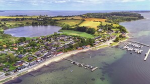 Luchtbeeld van een kustdorp met huizen, een jachthaven en een meer.