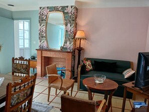 A living room with a fireplace, a sofa, a television, and a dining area with chairs and a table.
