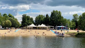 A lakeside park with tents, a sandy beach, and a boat.