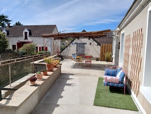 A patio with a table and chairs, potted plants, and a blue chair.