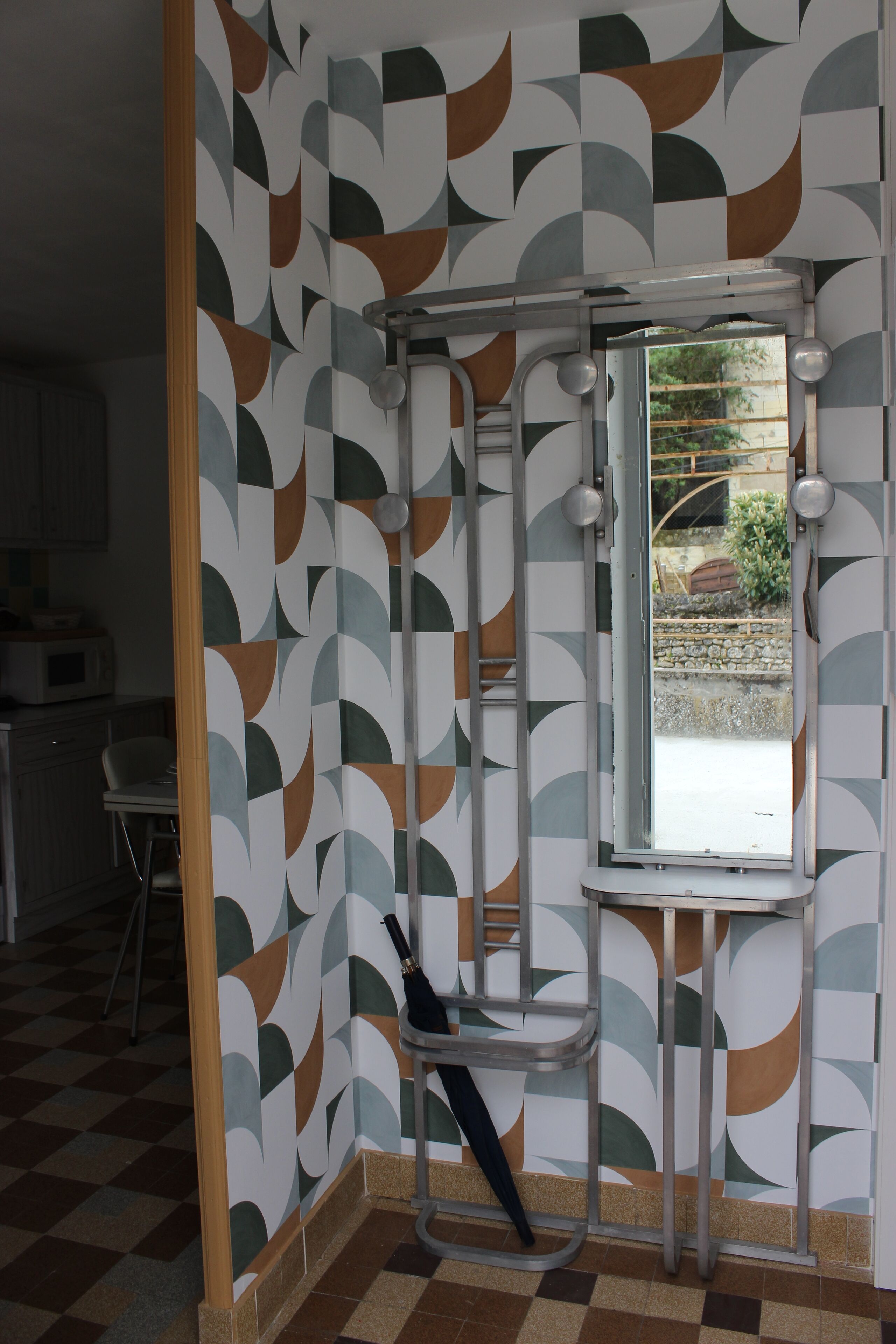 Un baño con pared de diseño geométrico, una ventana y zona de ducha.