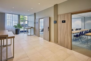 A modern hotel lobby with a long reception desk, a seating area with tables and chairs, and large windows providing natural light. - Courtyard by Marriott Dortmund (Dortmund)