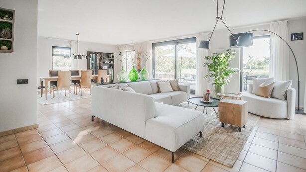 A spacious living room with a white sofa, a dining area with a table and chairs, and a kitchen in the background. - 4 bedroom lovely home in Havelte (Havelte)