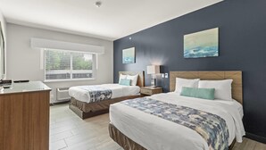A hotel room with two beds, a desk, and artwork on the walls. - Wingate by Wyndham Humble/houston Intercontinental Airport (Humble)