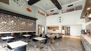 A spacious hotel lobby with multiple seating areas, a reception desk, and a modern design. - Wingate by Wyndham Humble/houston Intercontinental Airport (Humble)