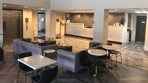 A hotel lobby with a reception desk, seating area, and elevator. - Wingate by Wyndham Humble/houston Intercontinental Airport (Humble)