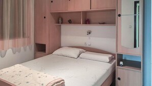 Ein Schlafzimmer mit Bett, Nachttisch, Kleiderschrank und Spiegel.