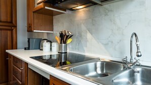 Una cocina con un lavamanos doble de acero inoxidable, armarios de madera, horno empotrado y cafetera.