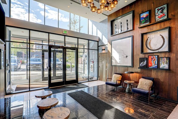 A hotel lobby with a glass entrance, a reception desk, and a seating area with a coffee table. - Ski-In/Ski-Out Resort Studio w/ Views in Park City (Park City)